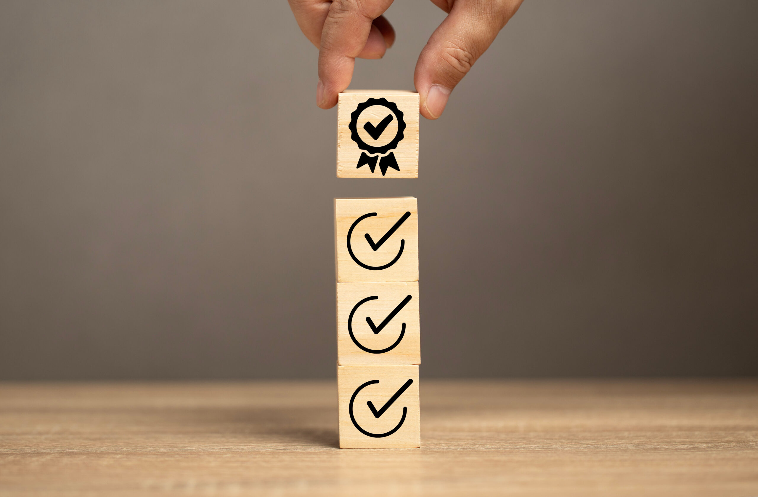 man put the certificate icon on wood cube into the right icon. iso certificate guarantee quality control in the marketing, finance and business industry. satisfaction concept.